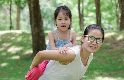 Portrait of woman carrying daughter while standing on field