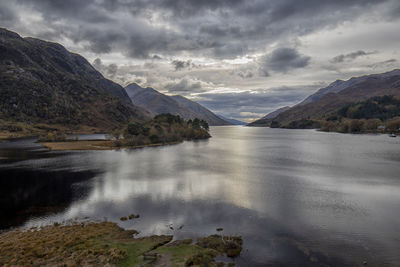 Scenic view of lake by mountains against sky