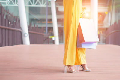 Low section of woman standing on footpath