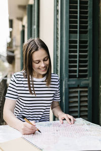 Young woman looking away while sitting on table