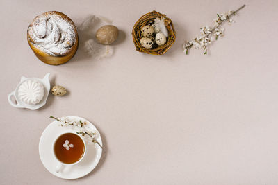 A beautiful easter still life with apple blossoms and a set of easter eggs in a nest, next to a cake