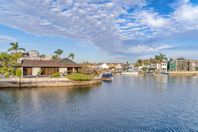 Buildings at waterfront against cloudy sky