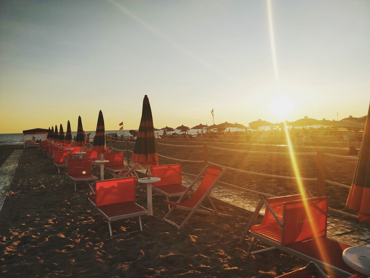 CHAIRS ON BEACH AGAINST BUILDINGS DURING SUNSET