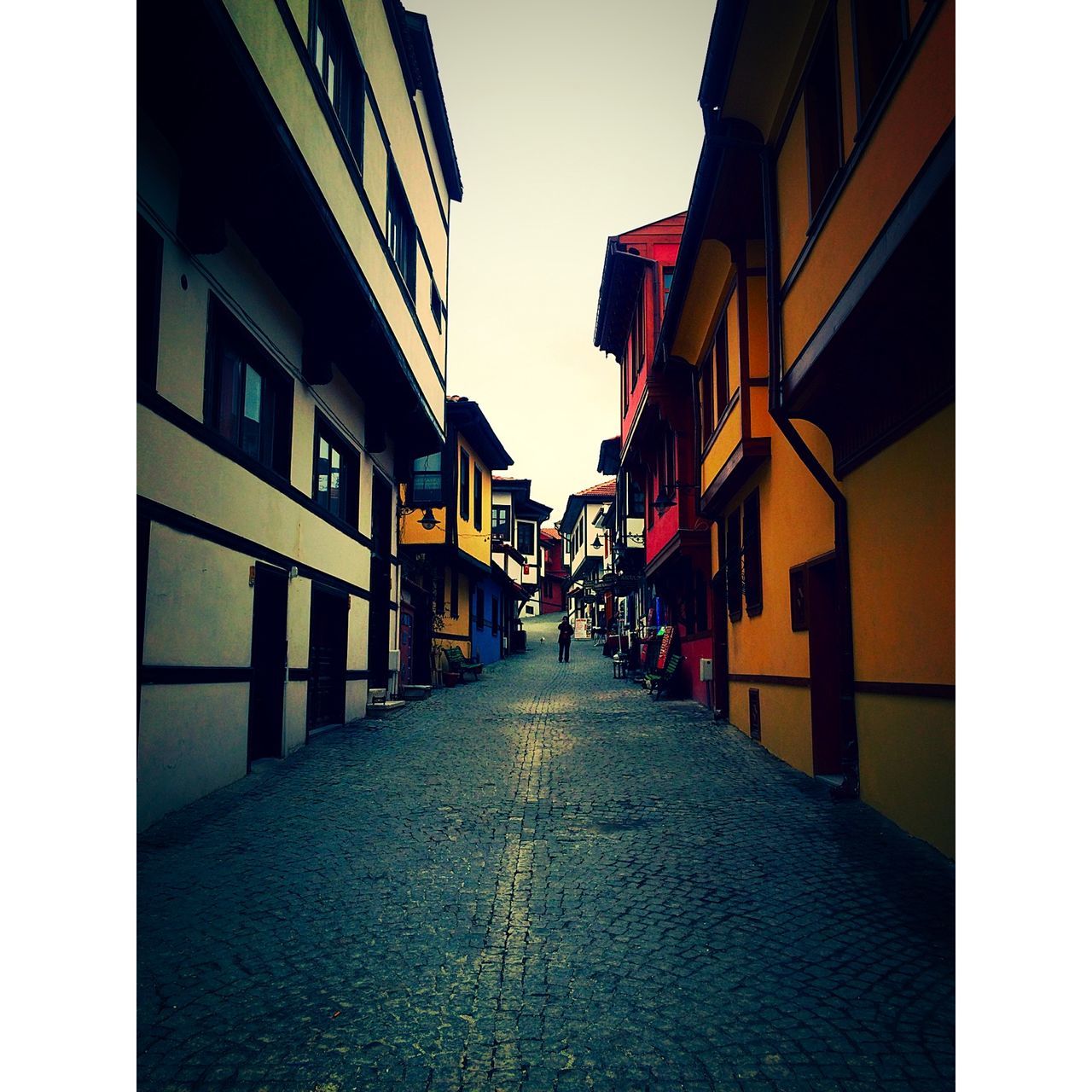 building exterior, architecture, built structure, the way forward, diminishing perspective, street, transfer print, city, residential structure, residential building, building, vanishing point, clear sky, transportation, narrow, auto post production filter, sky, alley, road, cobblestone