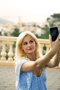 Graceful blonde woman in her 40s taking selfies