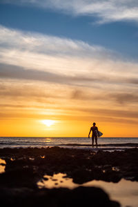 Silhouette person on beach against sky during sunset