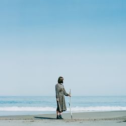 Rear view of person on beach against clear sky