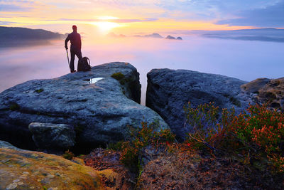 Sharp rear man silhouette on rocky peak. hiker enjoy view. tall man on rocky cliff watching down