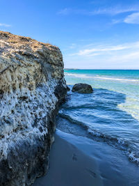 Rock formation on beach against sky