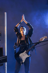 Portrait of woman with arms raised standing against sky