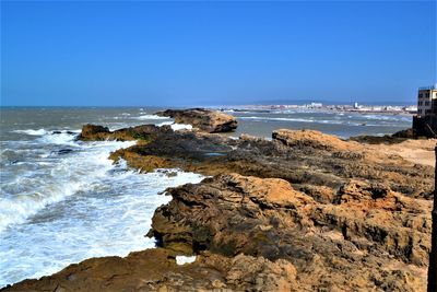 Rock formation on beach against clear blue sky