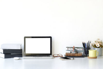 View of laptop on table against white wall