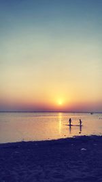 Silhouette people on beach against sky during sunset