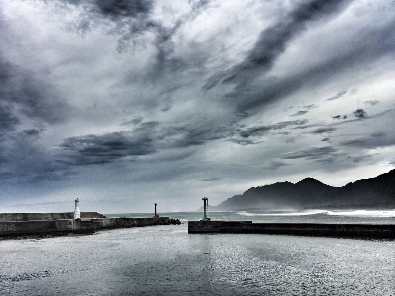 water, tranquility, waterfront, tranquil scene, sea, scenics, beauty in nature, mountain, nature, river, calm, ocean, sky, cloud - sky, cloudy, day, outdoors, shore, no people, non-urban scene, coastline, suspension bridge, remote