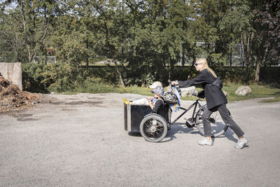 Mother pushing bicycle with children in carriage