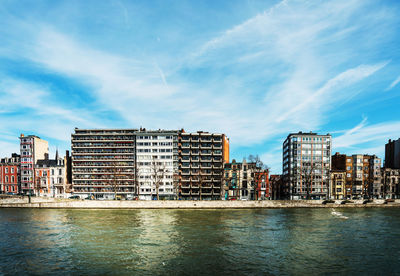 Buildings by river against sky in city