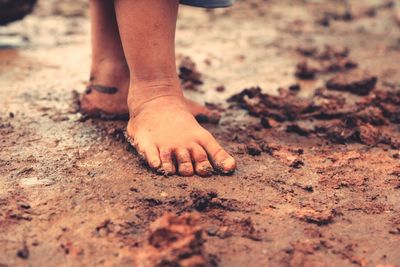 Low section of child standing on muddy field