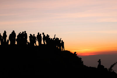 Silhouette people standing against sky during sunset