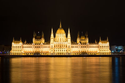 Illuminated hungarian parliament building by danube river at night