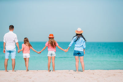 Rear view of women standing at beach against sky