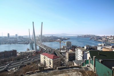 Cityscape by sea against clear blue sky