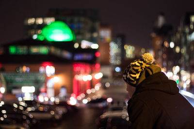 Rear view of man in illuminated city at night