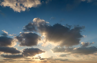 Low angle view of sunlight streaming through clouds