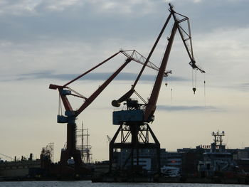 Cranes at commercial dock against sky