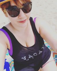 Close-up portrait of young woman wearing sunglasses at beach