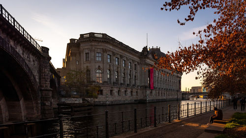 Bridge over canal amidst buildings in city against clear sky