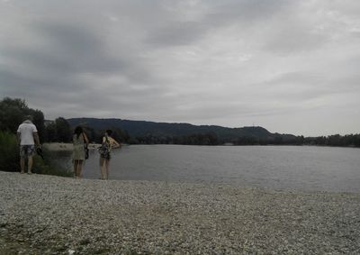 People on lake against sky