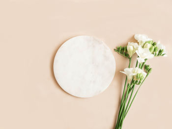 Marble  round podium and bouquet of freesia on beige background. place, background for cosmetics