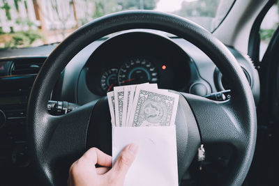 Close-up of cropped hand with paper currency in car