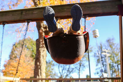 Low section of boy on swing against trees