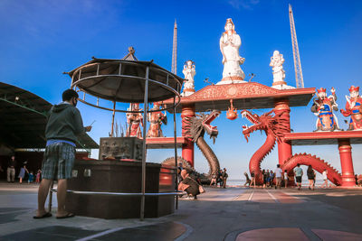 People at amusement park against blue sky