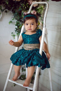 Girl sitting on a white staircase step ladder in white room