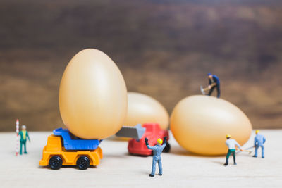 Close-up of figurines with eggs and toy trucks on table