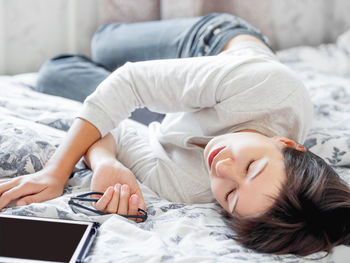 Woman in glasses are lying in bed with tablet. she is tired and sleeping after work online. 