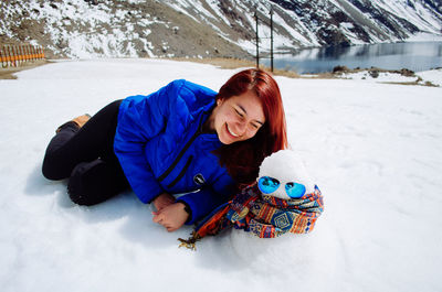 Young woman lying down on snow covered land