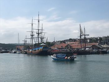 Sailboats moored at harbor against sky