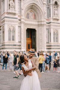 Young couple embracing while standing against building