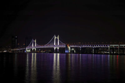 Illuminated suspension bridge over river at night