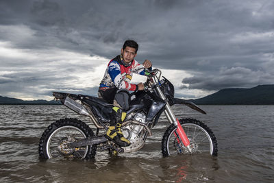 Man posing on his dirt-bike in a lake near pak chong / thailand