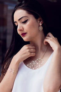 Close-up of young woman trying necklace while standing in store