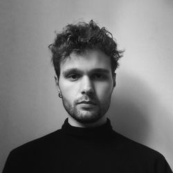 Portrait of young man standing against wall