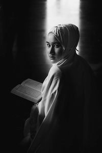 Portrait of young woman in hijab reading koran