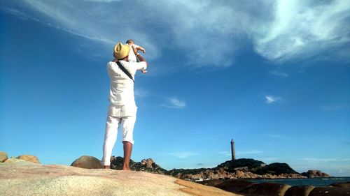Low angle view of man standing on landscape against blue sky