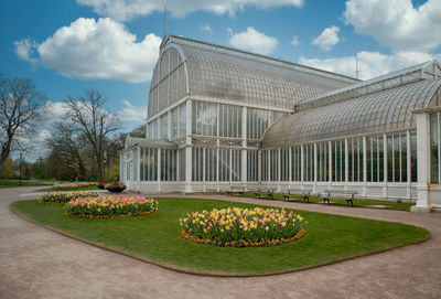 Lawn by building against cloudy sky