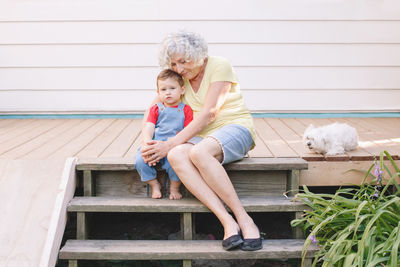 Happy senior woman sitting with grandson and dog outdoors