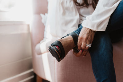 Low section of woman wearing sandal while sitting at home